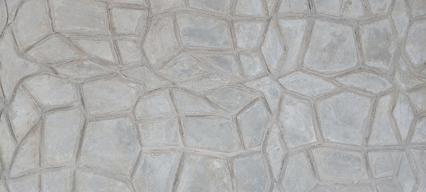 Molded texturized and patterned cement screed floor in custom and abstract geometrical patterns as raw concrete background texture.