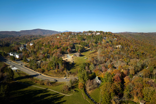 View from above of expensive residential houses high on hill top between yellow fall trees in suburban area in North Carolina. American dream homes as example of real estate development in US suburbs.