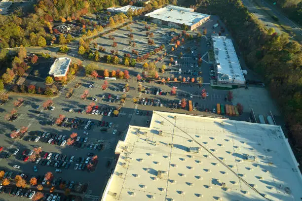 Photo of View from above of american grocery store with many parked cars on parking lot with lines and markings for parking places and directions. Place for vehicles in front of a strip mall center