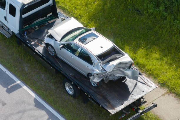 Tow truck hauling smashed vehicle on car accident site. Emergency services personnel responding to traffic crash on American street. First responders helping on road in the USA. grúa que transporta un vehículo destrozado en el lugar del accidente automovilístico. personal de los servicios de emergencia que responde a un accidente de tráfico en una calle estadounidense. los socorristas ayudan en la carretera en los ee. uu.