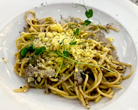 Pasta spaghetti chicken truffle with truffle cream, mushroom, and baby spinach served on natural stone terrazzo table.