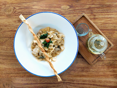 Spaghetti Chicken Alfredo with baby spinach served on a white plate on a wooden table