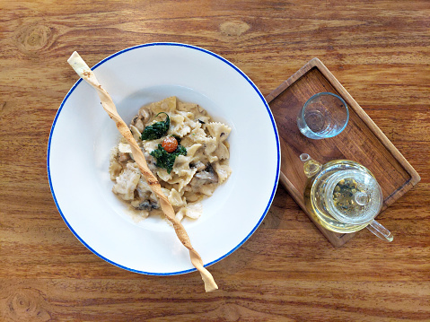 Spaghetti Chicken Alfredo with baby spinach served on a white plate on a wooden table