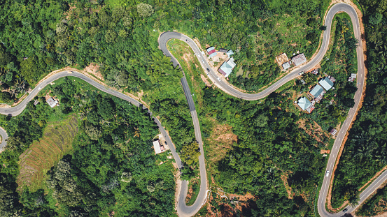 Flores Island Indonesia. Winding Mountain Road through Green Rice Terraces and Rural Agriculture Fields on Flores Island. Mountain Country Road towards Labuan Bajo City. Drone Point of View from directly above. Flores Island, East Nusa Tenggara, Lesser Sunda Islands, Indonesia, Southeast Asia