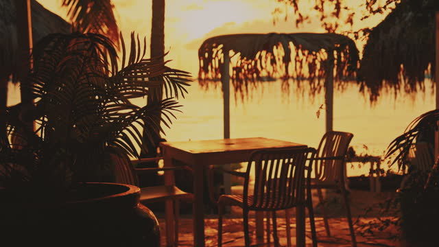 SLO MO Magic Light: Lockdown Shot of Chairs and Tables at Beach Restaurant during Bright Sunset