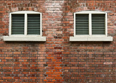 Red brick wall  or red exposed brick weathered texture on a heritage abandoned colonial building. With louvred window. Seamless texture. No people.