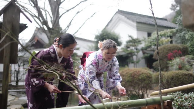 Female friends purifying hands at “Chozusha” in temple