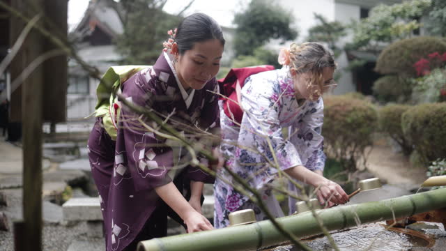 Female friends purifying hands at “Chozusha” in temple