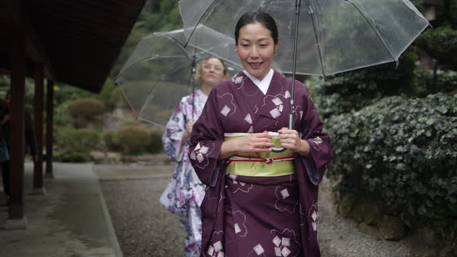 Women in kimono walking in temple in a rainy day