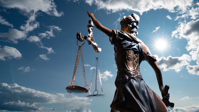 the statue of justice turns against the backdrop of clouds moving across the blue sky. time lapse 4k.
