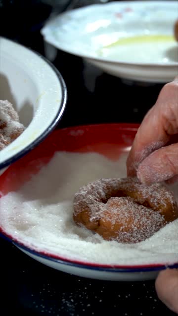 Slow motion. A person coats delicious fried donuts with sugar