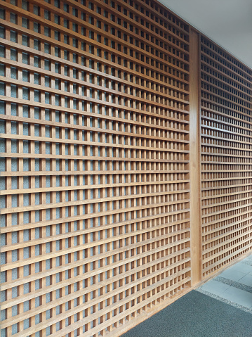 Modern natural wood slats with stone background. Modern Zen Japanese wall wooden fluted panel in grid and checkerboard arrangement functions as the double skin for architectural façade finishing.