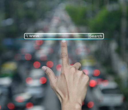 Hand pressing search www button over blur of rush hour with cars and road in city, Searching system and internet concept