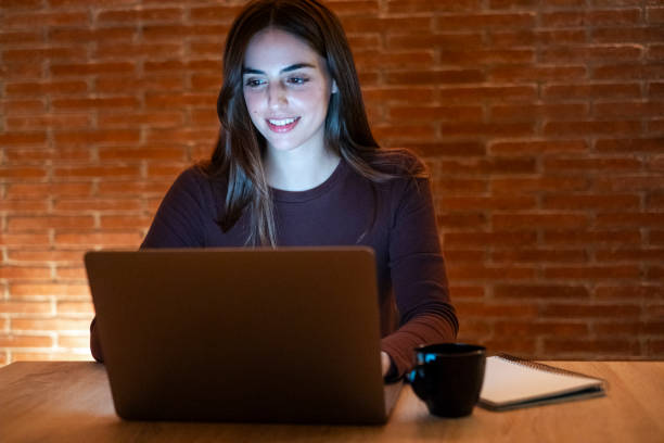 istock Portrait of young happy woman using laptop at night, using modern technology havinmg fun with glowing screen in dark office or at home, startup business meeting online with businesswoman 2124361598