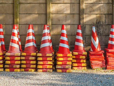 Red traffic cones stacked alongside a wall at a roadworks depot