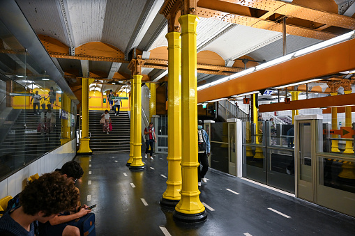 Paris, France, June 30, 2022. Shot at the Gare de Lyon metro station, the widespread use of the color yellow is striking. People wait along the platform.