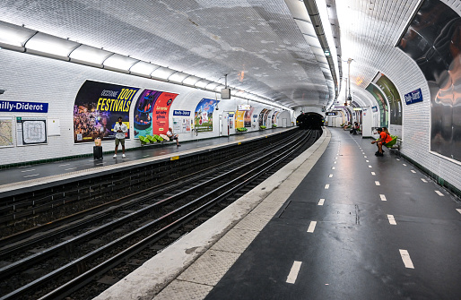 Paris, France, June 30, 2022. At the Reuilly - Diderot metro stop, the perspective highlights the white tiled covering of the stop. People wait for the train to arrive.