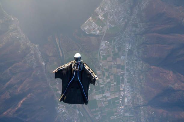 istock Wing suit flier soars above mountain landscape 2124397121