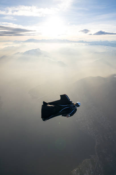 istock Wing suit flier soars above mountain landscape 2124399144