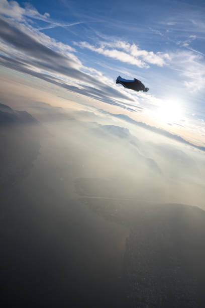 istock Wing suit flier soars above mountain landscape 2124401316