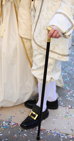 man with noble clothes and nineteenth-century shoes with walking stick during carnival