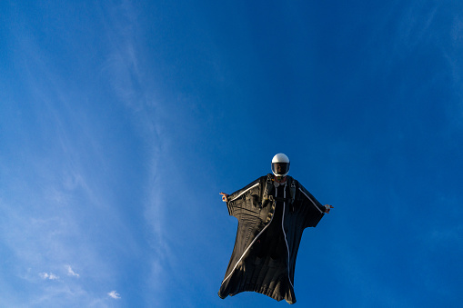 Wing suit flier soars in blue skies