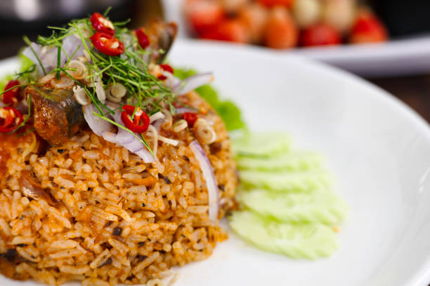 Thai food, Fried jasmine rice with canned fish mackerel in tomato sauce, topped with red chili, red onion, lettuce and kaffir lime leaves.