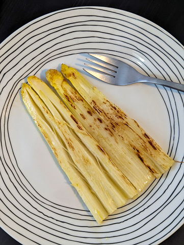 Cooked and roasted white asparagus, ready to eat, on a plate, overhead view