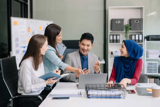 istock Happy businesspeople while collaborating on a new project in an office. Group of diverse businesspeople using a laptop and tablet 2124476656
