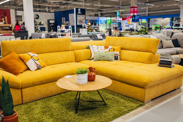 istock A yellow sofa bed displayed in a department store, with decorative pillows, a rug in front of it and a coffee table 2124485418