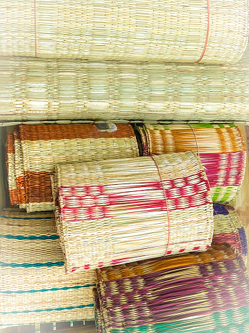 A collection of meticulously handcrafted rags is showcased, stacked with precision. The diverse colors and patterns reflect the artisans skill, revealing a range of hues from natural tans and browns to vibrant reds, greens, and purples. The creativity and tradition of rag weaving are evident in the intricate designs and varying sizes of the pieces.