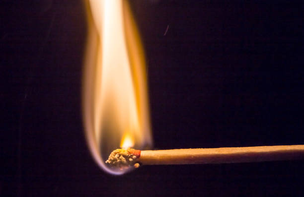 Burning match isolated on black background with smoke clouds. Macro photo.
