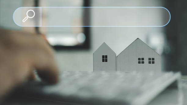 istock Man using keyboard with blank search bar and model home, search for find information data about home. 2124552391