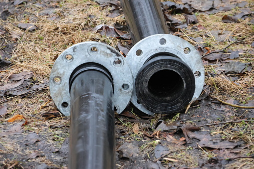 Clear bolts and screws. The pipes are located on the ground in nature.