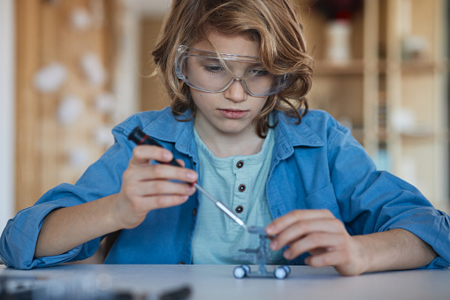 School boy, working on his prototype of a robot at home. The best school project ever.