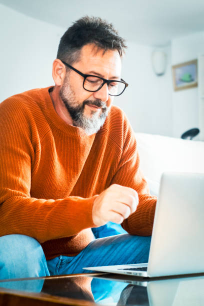 istock Handsome serious man sits on sofa with computer on laps, spend time at home web surfing information, use modern tech, make order on internet. Freelancing, telework, new software. Small online business 2124610791