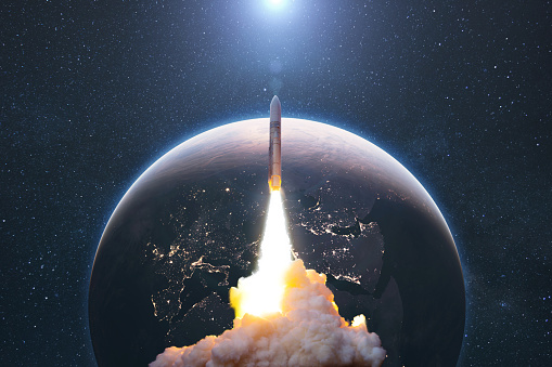 Space rocket lift off into cosmos with smoke and blast on a background of the blue planet earth. Spacecraft flies in space with a starry sky near the planet. Successful start of the mission