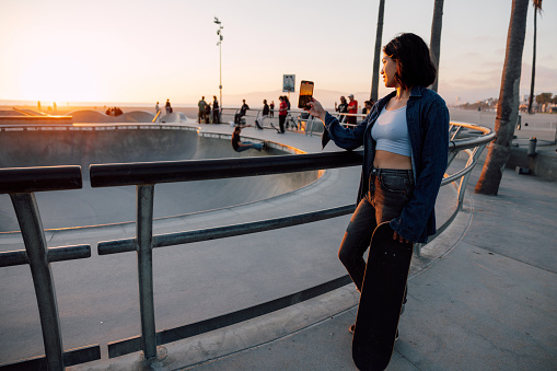 Woman taking beautiful shots at the skate park with a golden sunset light by the beach.