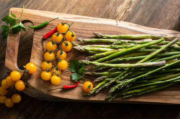 branch with yellow cherry tomatoes, asparagus, hot peppers and Brussels sprouts on a wooden board. View from above