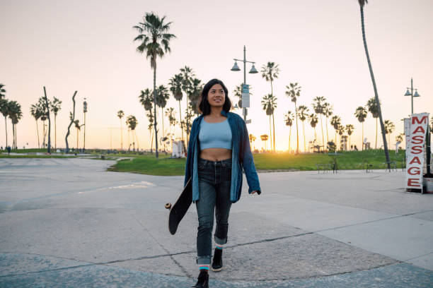 istock Young woman walk back home from Venice beach with her skateboard 2124623571