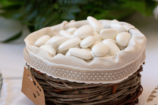 a rustic basket filled with traditional white sugared almonds, a sweet favor for a wedding celebration