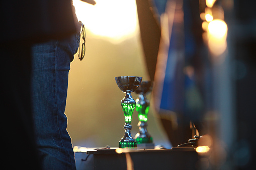 The sun sets casting a warm glow on a trophy, highlighting the moment of achievement at an awards ceremony