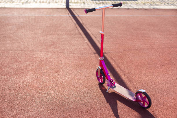 A small kid's scooter stands on the sidewalk. High quality photo
