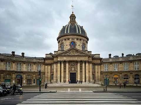 Paris, France - 19.02.2024. Institut de France, Paris. Grand cupola-topped building in baroque style, the headquarters of 5 French intellectual academies. The famous Institut de France in Paris on a gloomy day