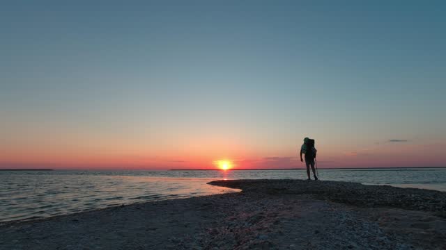 A man with a backpack walks along the Kinburn Spit in the early morning.