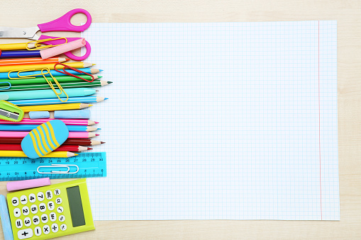 Blank sheet of paper with different school supplies on brown wooden table