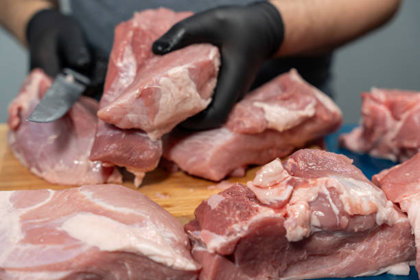 istock A man in black latex gloves cuts pork on a cutting board. 2124768900