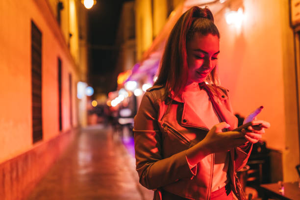 istock Beautiful young woman using a phone outdoors at night 2124788944