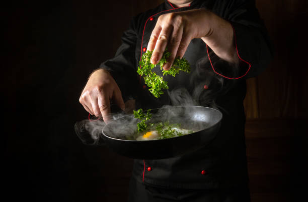 istock The chef throws fresh parsley into the scrambled eggs in a frying pan with his hand. Low key concept of preparing a delicious breakfast in a restaurant kitchen. Asian cuisine 2124789981