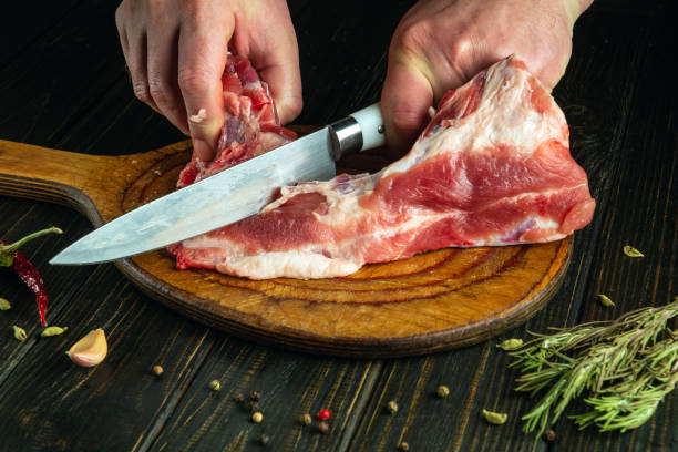 istock A cook cuts raw meat with a knife on a cutting board before preparing a meat dish. Recipe idea for a hotel or restaurant 2124793253